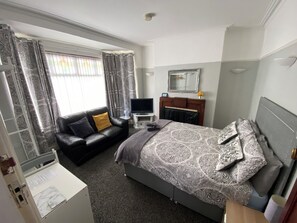 A hotel room with a bed, a sofa, a TV, a desk, and a mirror. - Crumlin Road Guesthouse (Belfast)