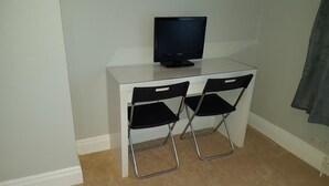 A small room with a white desk, a black television, and two black chairs. - Crumlin Road Guesthouse (Belfast)