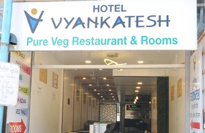 La entrada al Hotel Vyankatesh, con un letrero que indica que es un restaurante vegetariano y ofrece habitaciones.