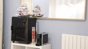 Una pequeña cocina americana equipada con refrigerador, microondas y un armario blanco en la parte inferior.