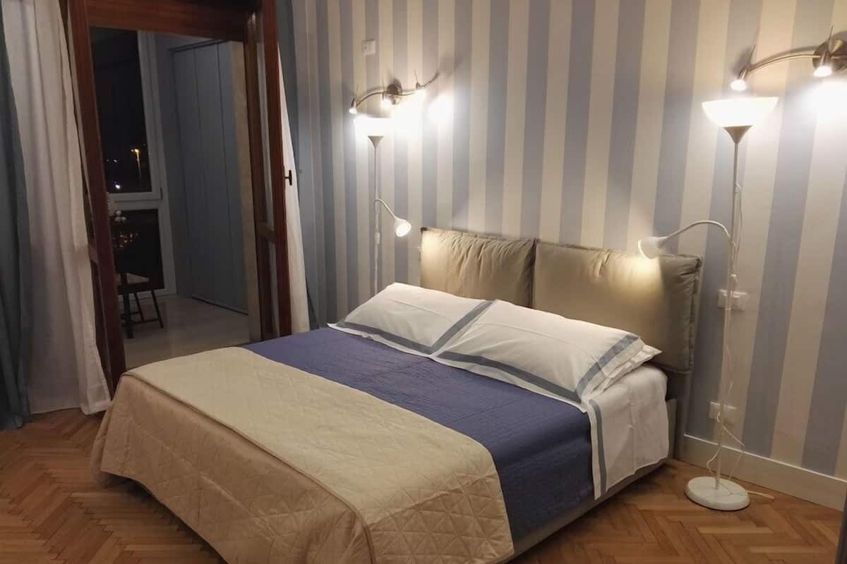Ein Schlafzimmer mit einem Bett, gestreifter Tapete und Nachttischlampen.