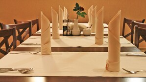 A dining table set for a meal with folded napkins, a vase with a flower, and a salt and pepper set. - Hotel Rural Puerta De Caderechas (Oña)