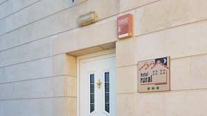 A hotel entrance with a white door, a sign indicating 'hotel rural', and a 'Fuego Castellan' sign above the door. - Hotel Rural Puerta De Caderechas (Oña)