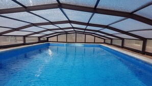 An indoor swimming pool with a clear blue water surface, surrounded by a glass ceiling and a tiled floor. - Hotel Rural Puerta De Caderechas (Oña)