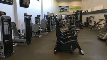 Ein Fitnessstudio mit verschiedenen Trainingsgeräten, darunter Cardiogeräte und Kraftstationen.