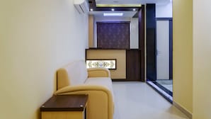 A modern hotel lobby with a reception desk, a waiting area with a sofa and a small table, and a patterned wall. - Treebo Oasis, Laxmisagar (Bhubaneshwar)
