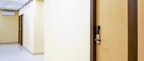 A hotel corridor with a door labeled '209', a modern ceiling with recessed lighting, and a plain wall.