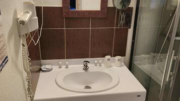 A bathroom with a white sink, a mirror, a towel rack, and a glass shower enclosure.