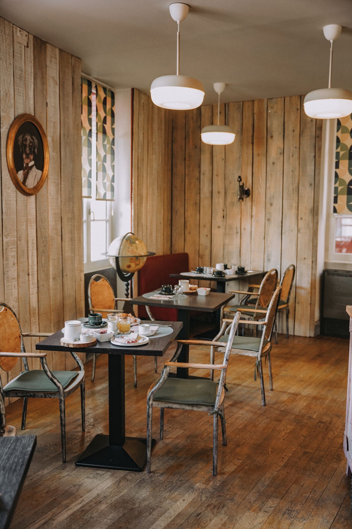 A wooden-paneled room with a dining table set for a meal, chairs, and hanging pendant lights.