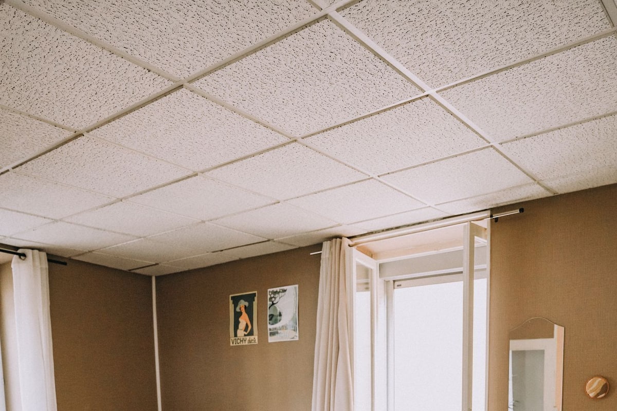 Un dormitorio con dos camas, un radiador, una ventana con cortinas y un espejo en la pared.