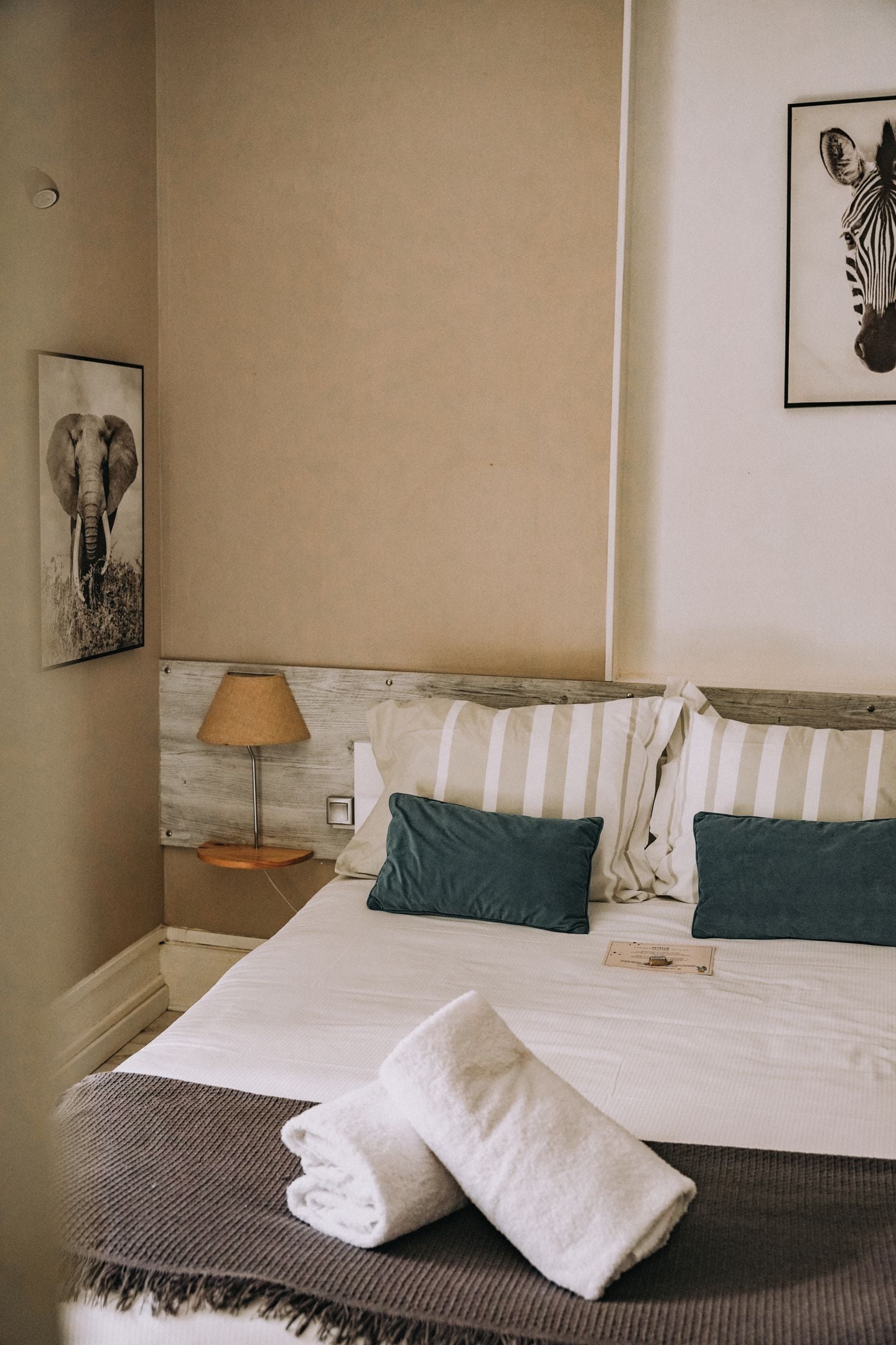 Ein ordentlich gemachtes Bett mit gestreiften Kissen, einer Lampe und einem gerahmten Bild an der Wand.