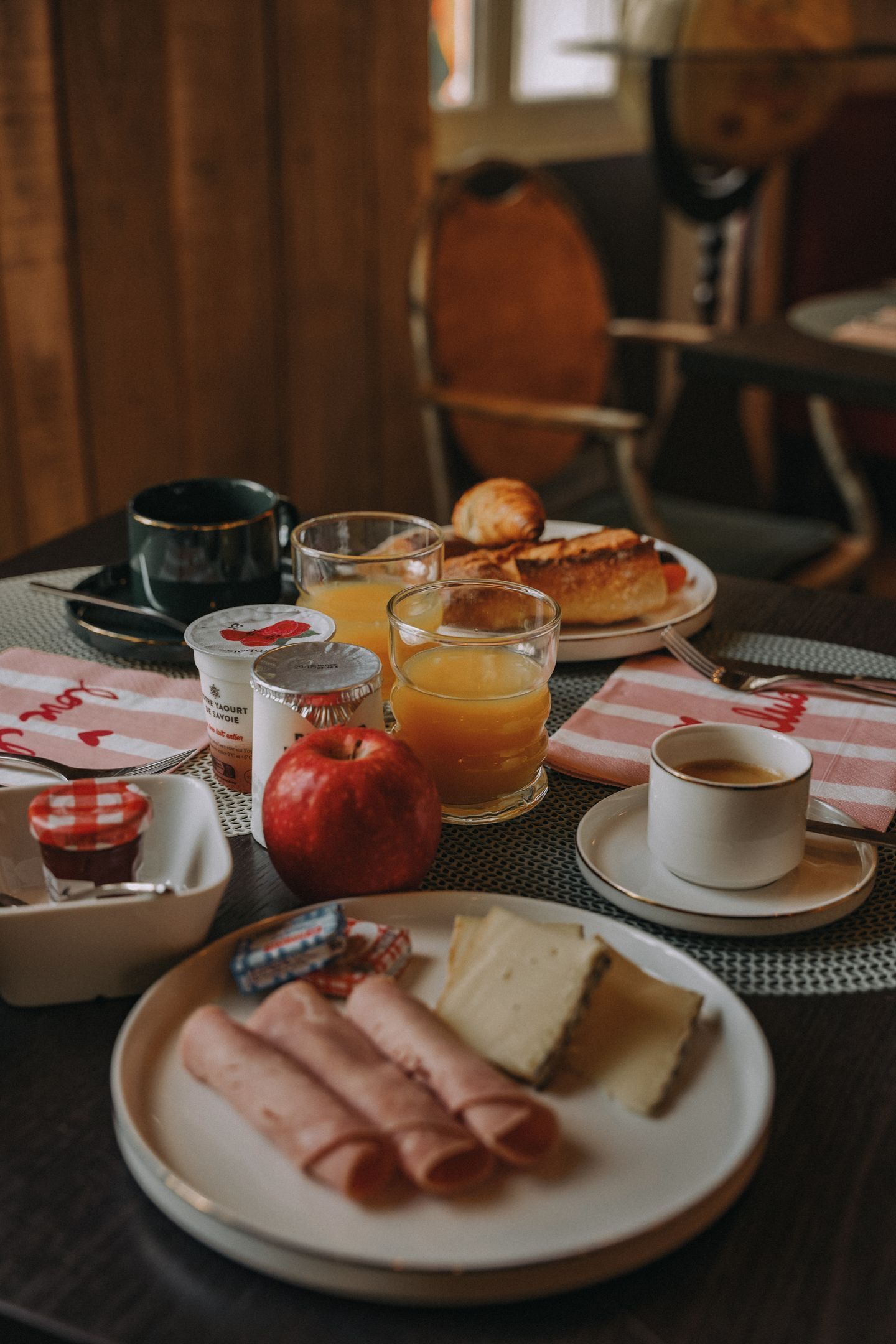 Una escena de desayuno con platos de comida, una taza de café y un vaso de zumo de naranja.