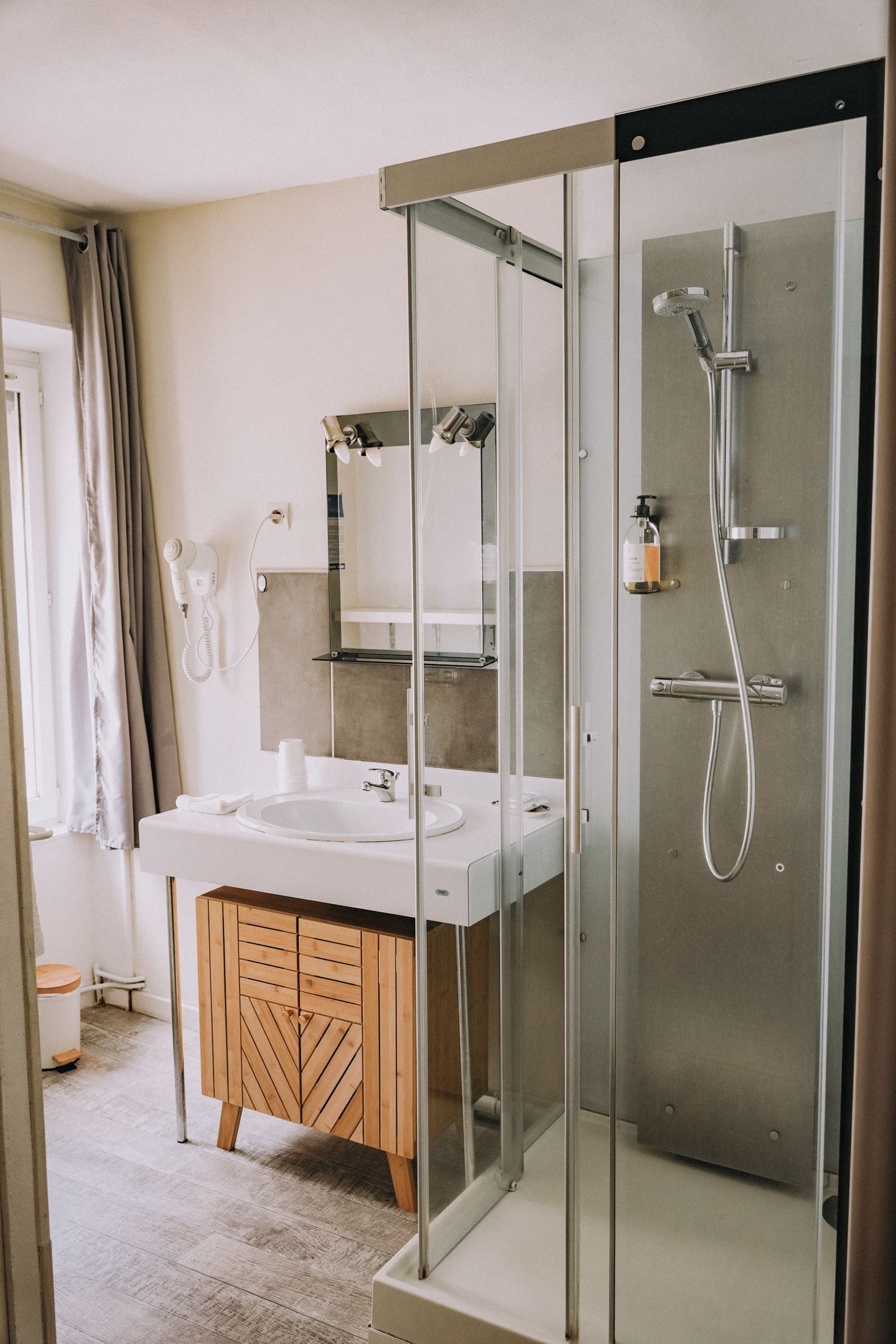 Un baño moderno con cabina de ducha de vidrio, tocador de madera y un espejo grande.