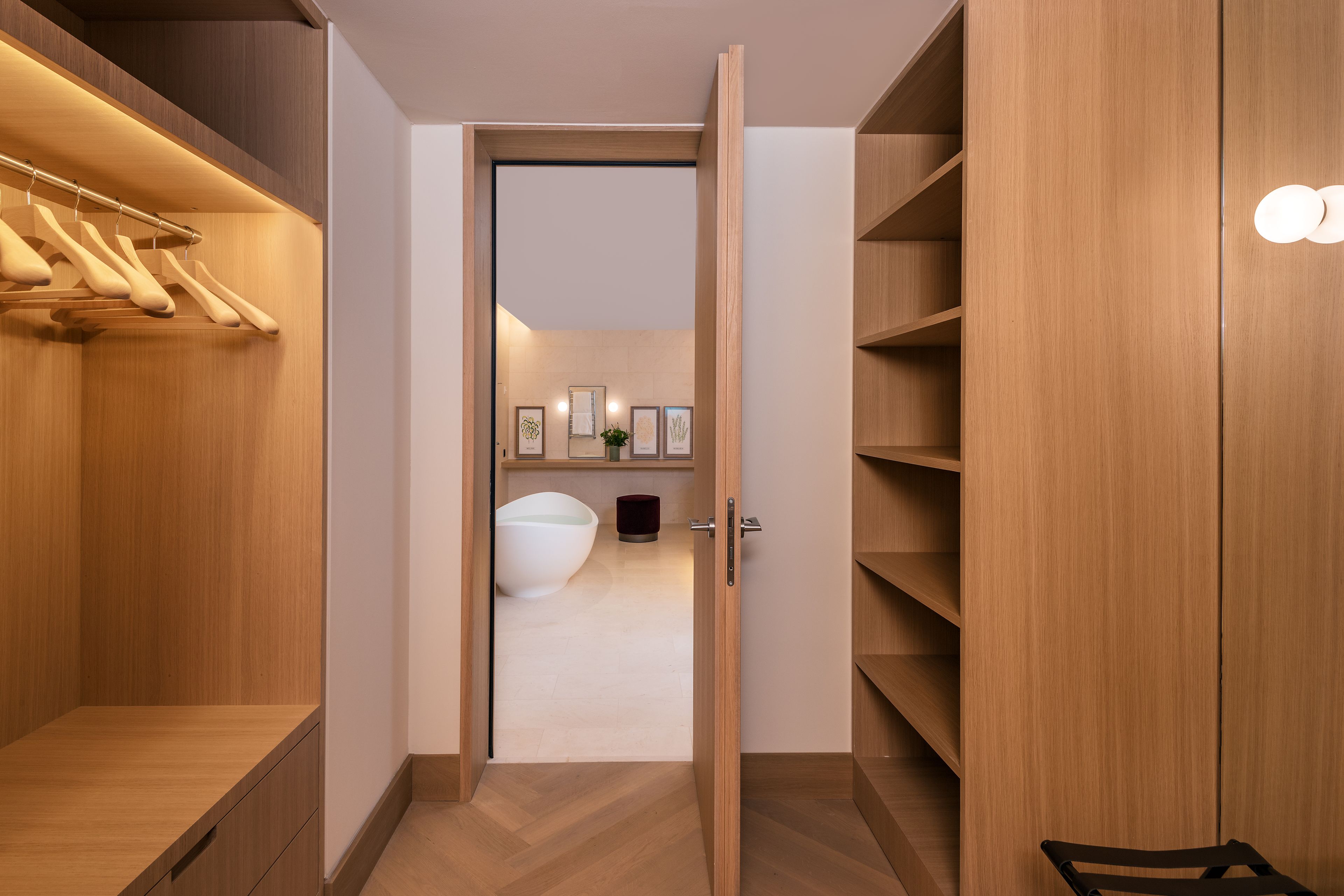 Un vestidor moderno con estantes de madera, una barra para colgar ropa y un espejo grande.