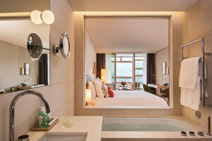 Un baño de hotel moderno con un espejo grande, una bañera y un lavabo.