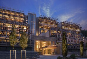 Un hotel moderno con una estructura de varios pisos, amplias ventanas y una entrada bien iluminada.