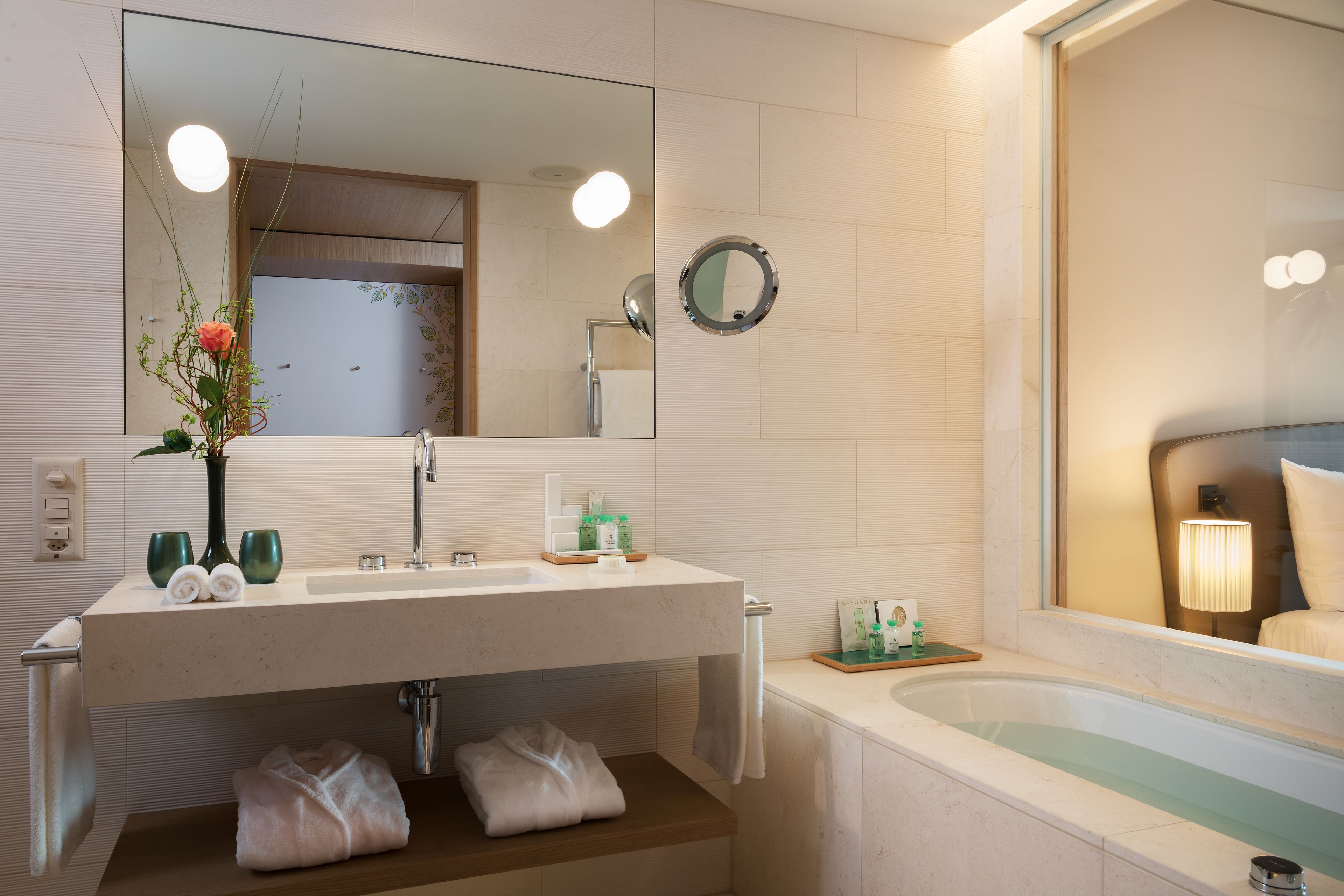 Uma casa de banho moderna com um espelho grande, uma sanita com artigos de higiene, uma banheira e um porta-toalhas.