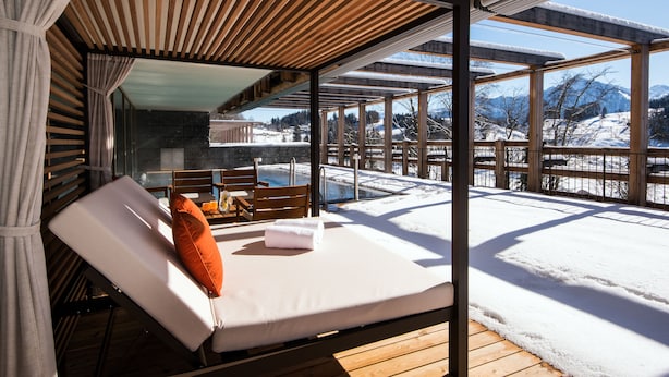 A sunlit room with a wooden deck, a glass wall, and a view of a snowy landscape. - Waldhotel by Bürgenstock Lake Lucerne (Ennetbuergen)