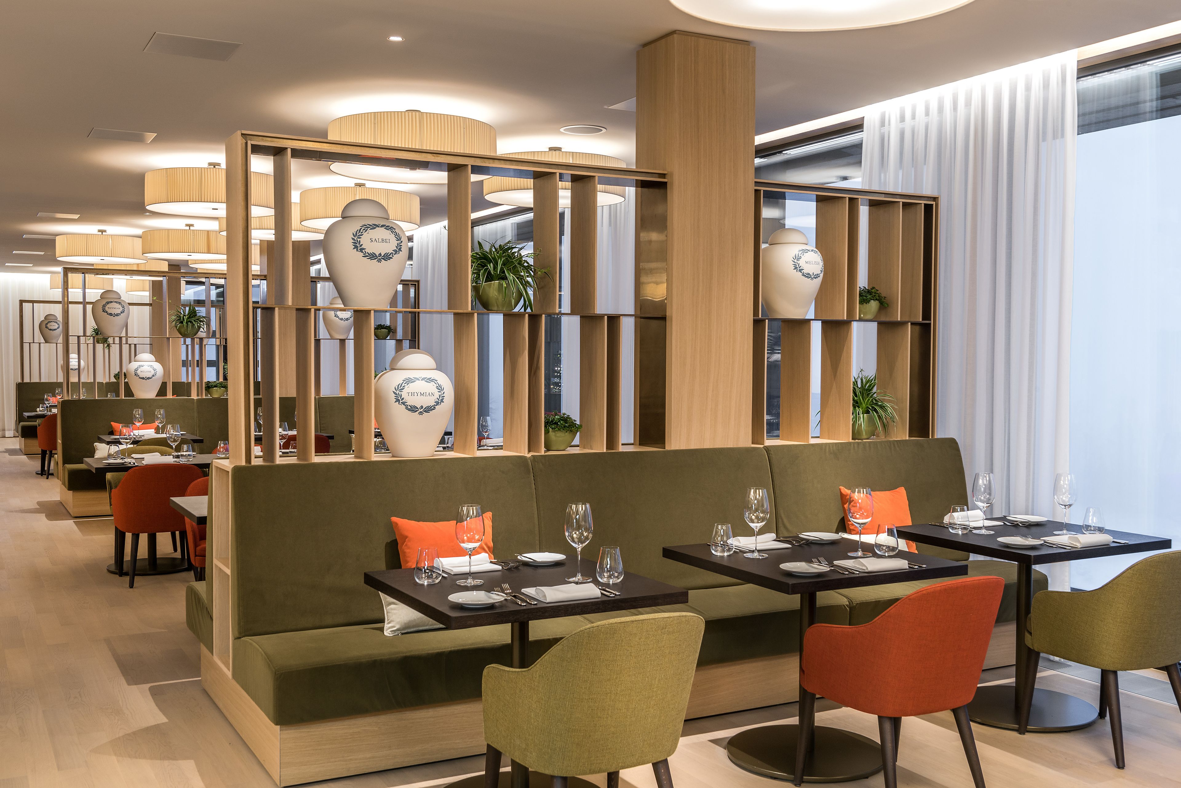 Un restaurante moderno con cabinas y mesas, separadores de madera y jarrones decorativos.
