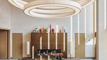 A modern living room with a fireplace, circular ceiling lights, and a wooden floor.