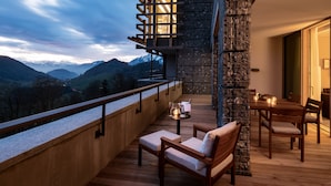 A balcony with a wooden deck, stone wall, and a table with chairs. - Waldhotel by Bürgenstock Lake Lucerne (Ennetbuergen)