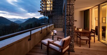 Un balcón con cubierta de madera, pared de piedra y una mesa con sillas.