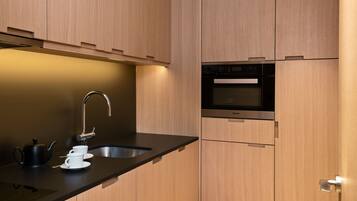 Una cocina moderna con armarios de madera, encimera negra, pileta de acero inoxidable y horno integrado.