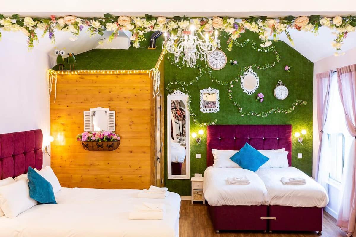 A bedroom with two beds, a wooden headboard, a mirror, and decorative wall elements.