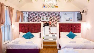 A hotel room with two beds, a chandelier, a floral wall, and a checkered floor.