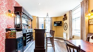 A bar area with a counter, stools, and a television mounted on the wall. - Honeypot House (Newcastle-upon-Tyne)