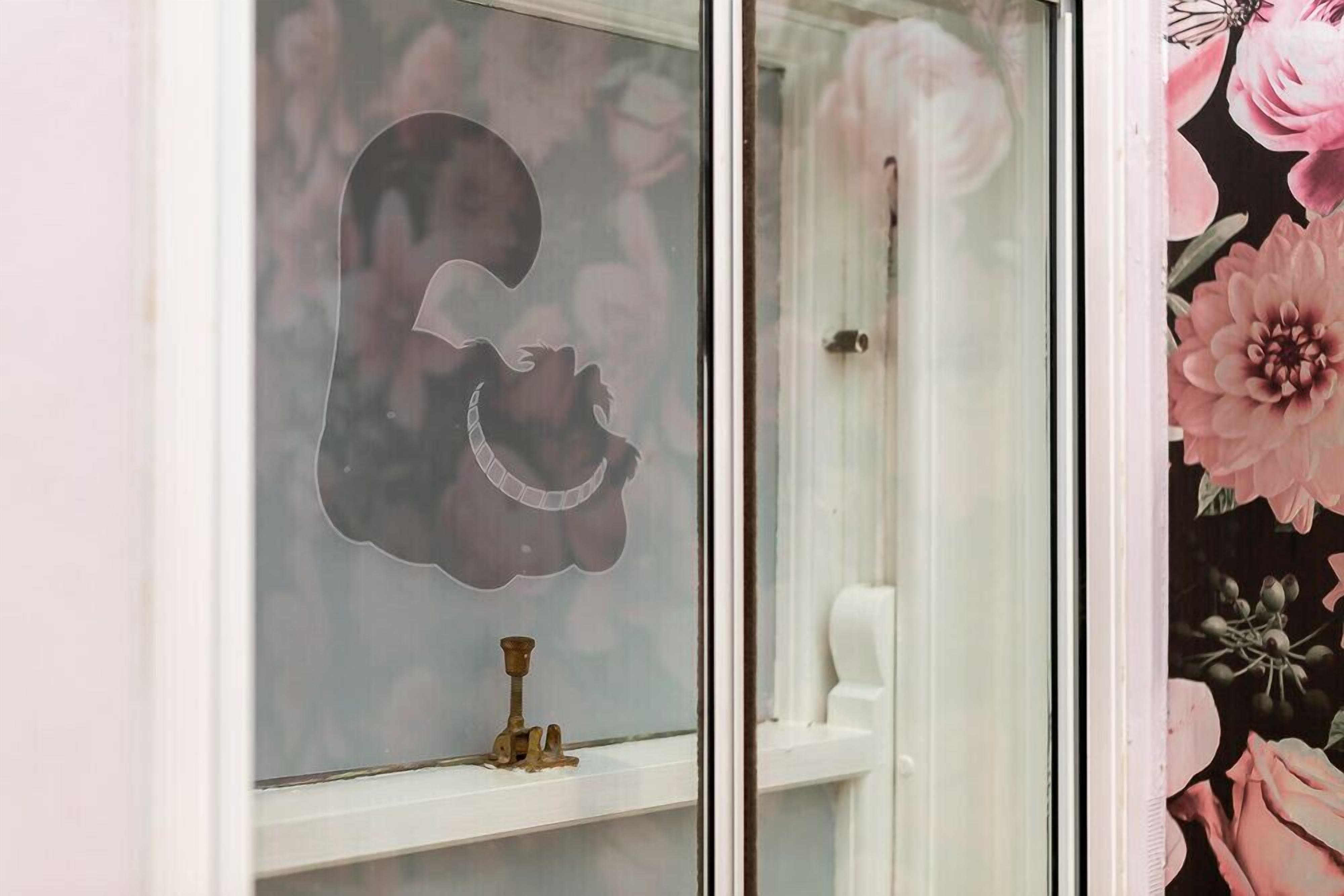 A window with a floral pattern and a brass object on the sill.