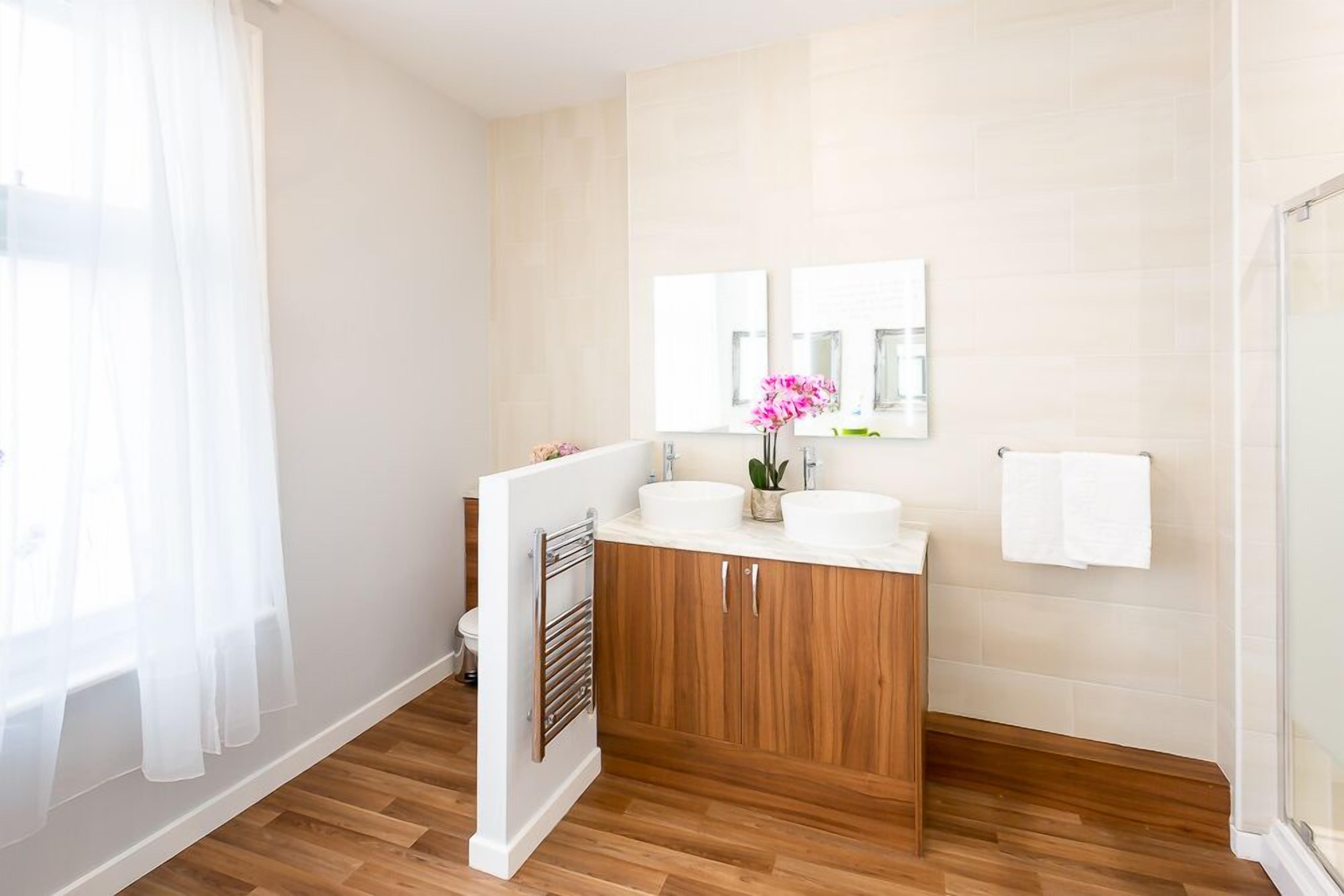 Un baño con armarios de madera, un lavabo blanco y un espejo.