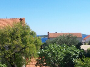 A coastal building with a red-tiled roof, surrounded by greenery and overlooking the sea. - Apartmani Lastavica (Orebic)