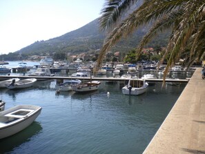 Una marina con varios barcos amarrados, rodeada por un paisaje montañoso y palmeras.