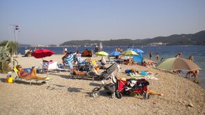 Una playa con tumbonas, sombrillas y una vista despejada del mar.