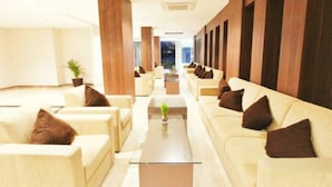 A spacious lobby with a central coffee table, sofas with brown cushions, and wooden paneling on the walls. - CoreHotel Malioboro City Yogyakarta (Depok)