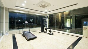 A modern gym with a treadmill, weight machines, and a large window offering a city view. - CoreHotel Malioboro City Yogyakarta (Depok)