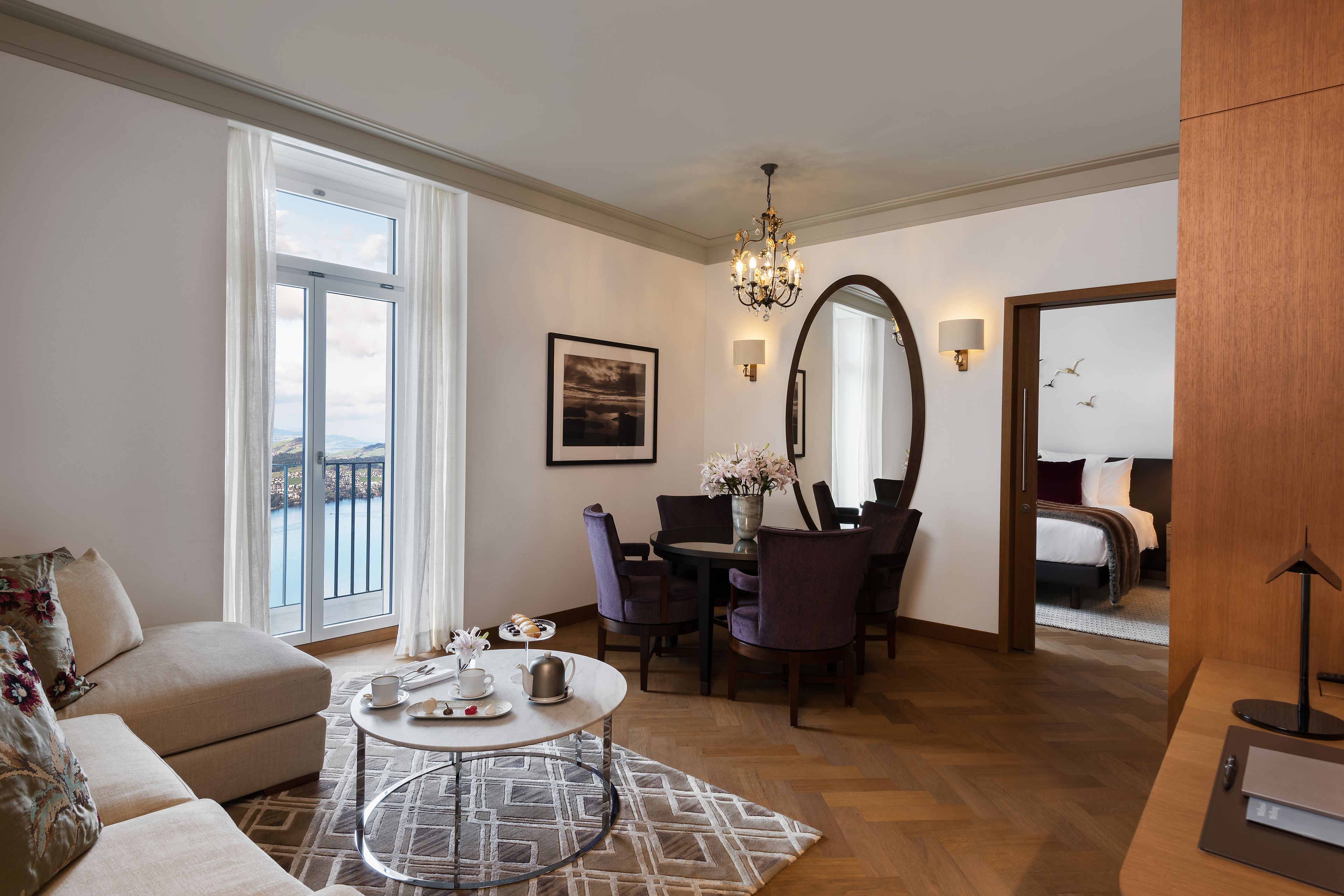 Ein Hotelzimmer mit Balkon, Essbereich, großem Spiegel und Bett.