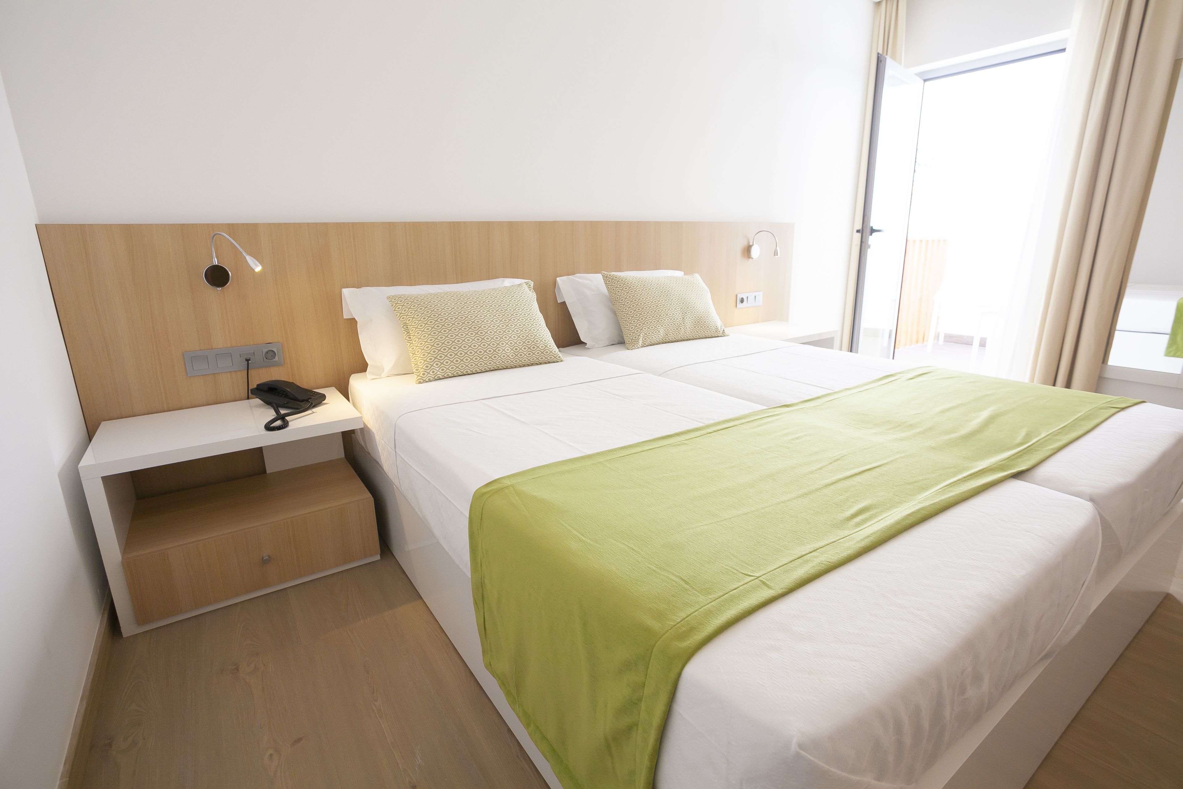 Une chambre d’hôtel équipée d’un lit, d’une table de chevet et d’un petit bureau avec un téléphone.