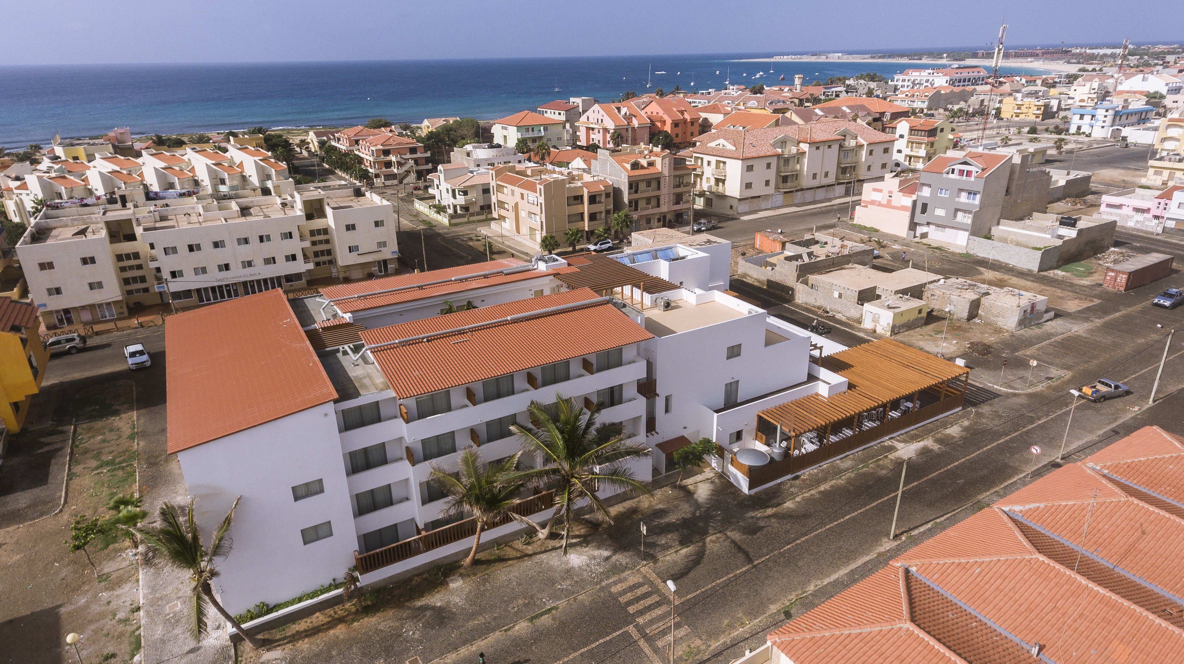 An aerial view of a coastal town with buildings, a beach, and the sea in the background.