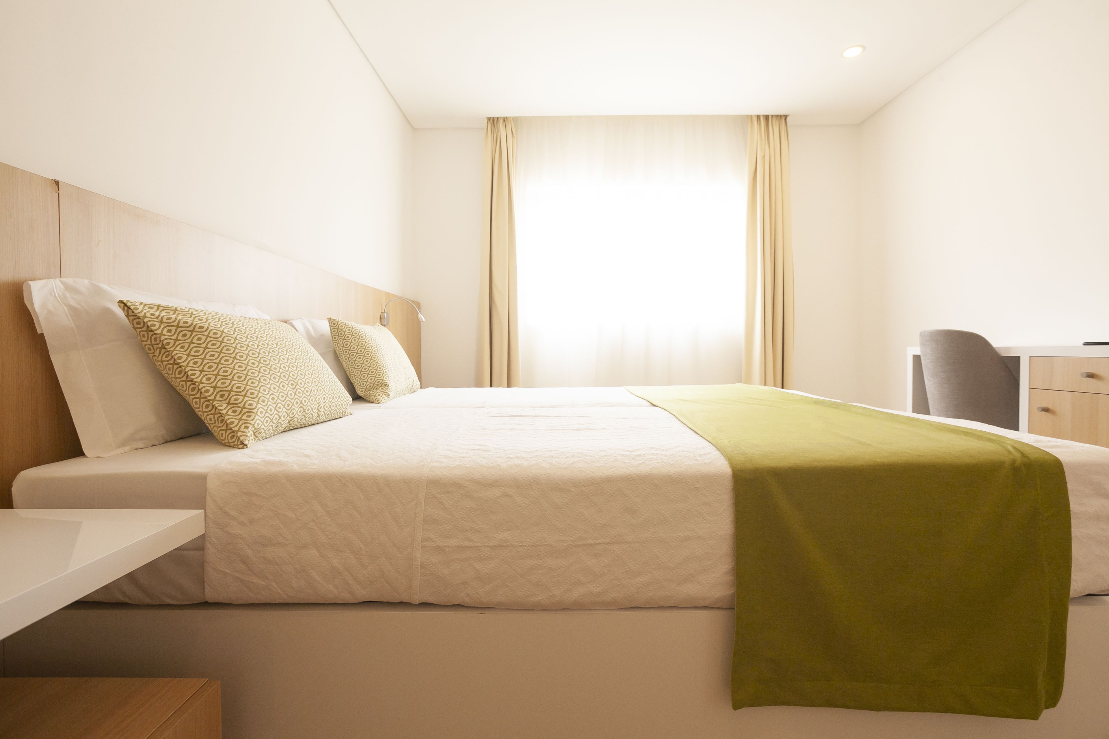 A hotel room with a bed, a desk, and a chair.