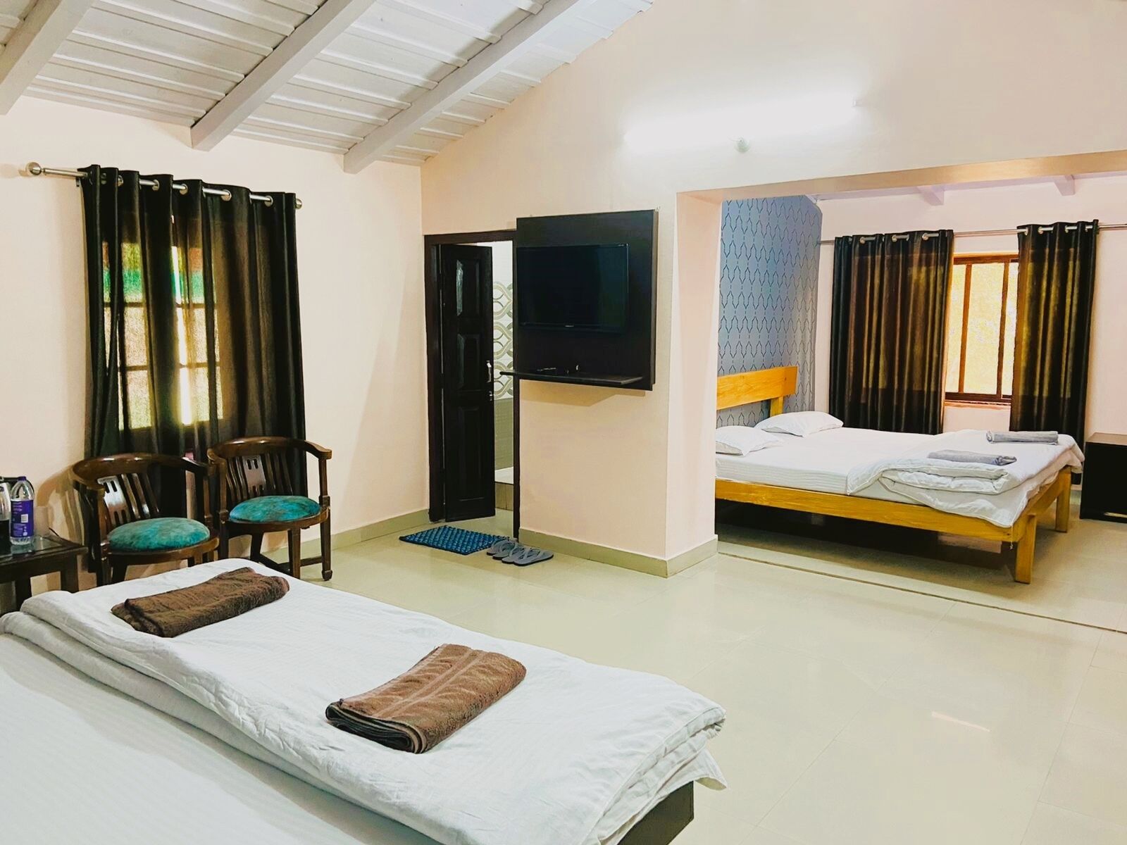 A hotel room with two beds, a TV, and a desk with chairs.
