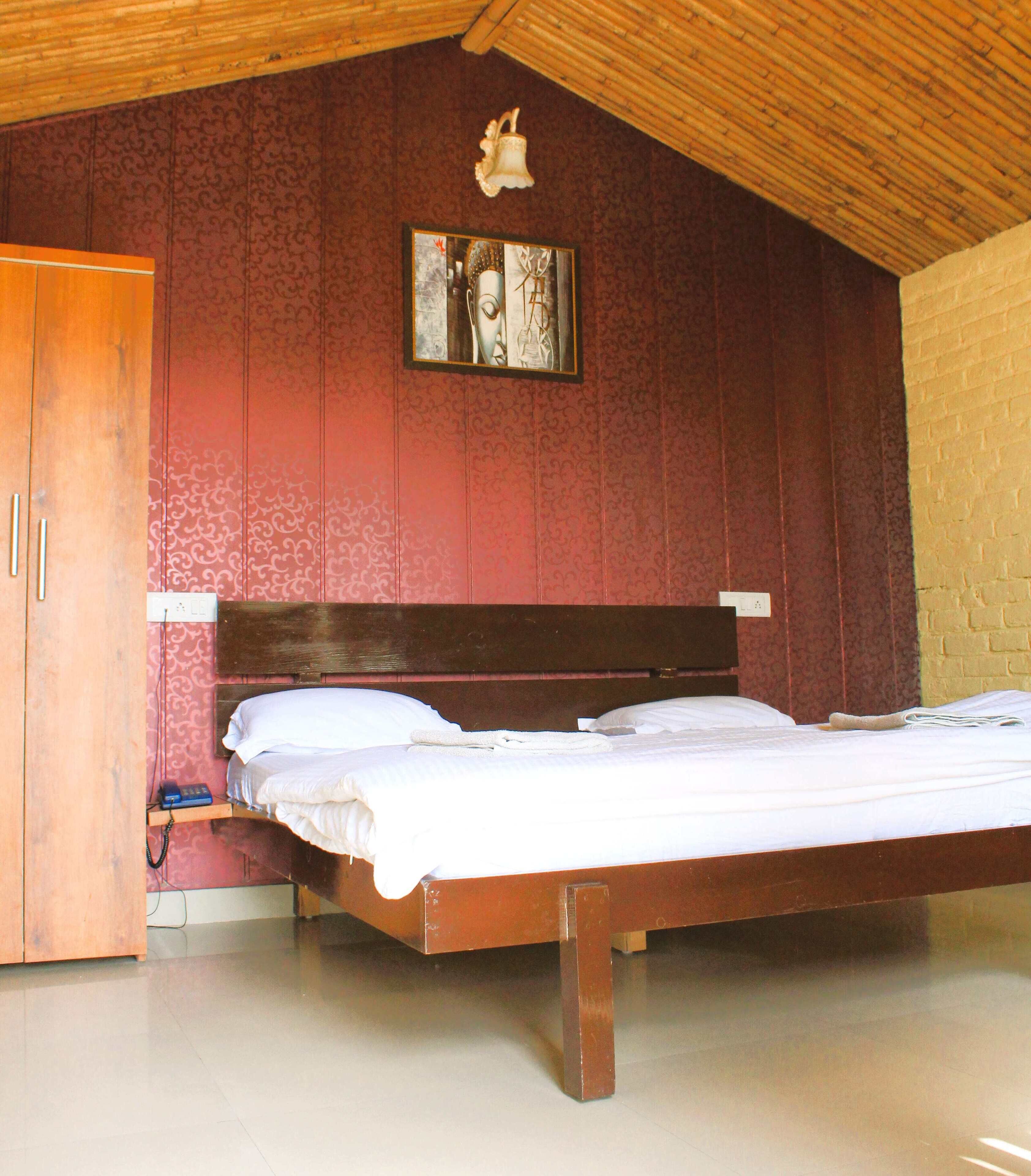 A bedroom with a wooden bed, a wooden wardrobe, and a wall-mounted light fixture.