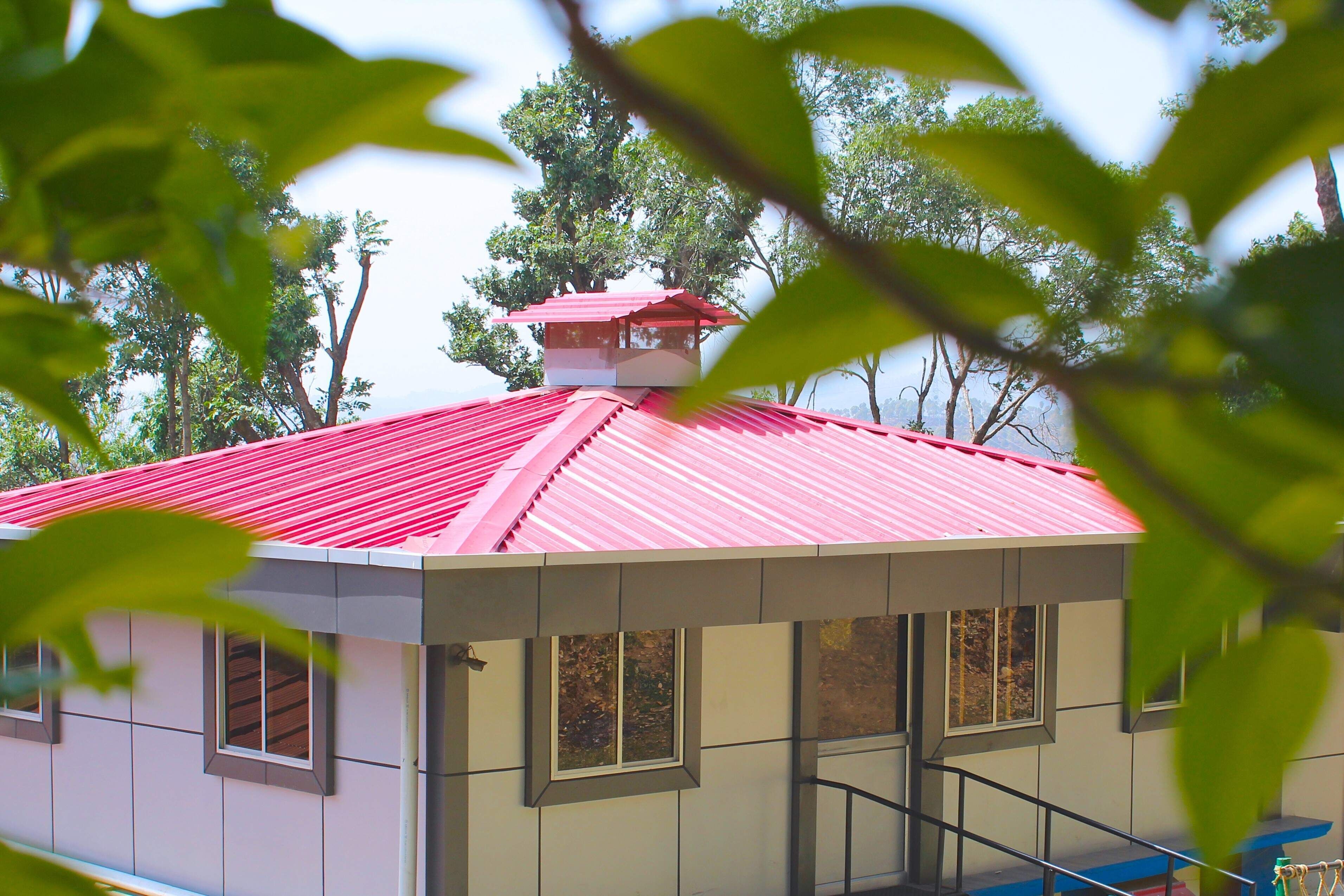 A building with a red roof, multiple windows, and a staircase leading to a balcony.