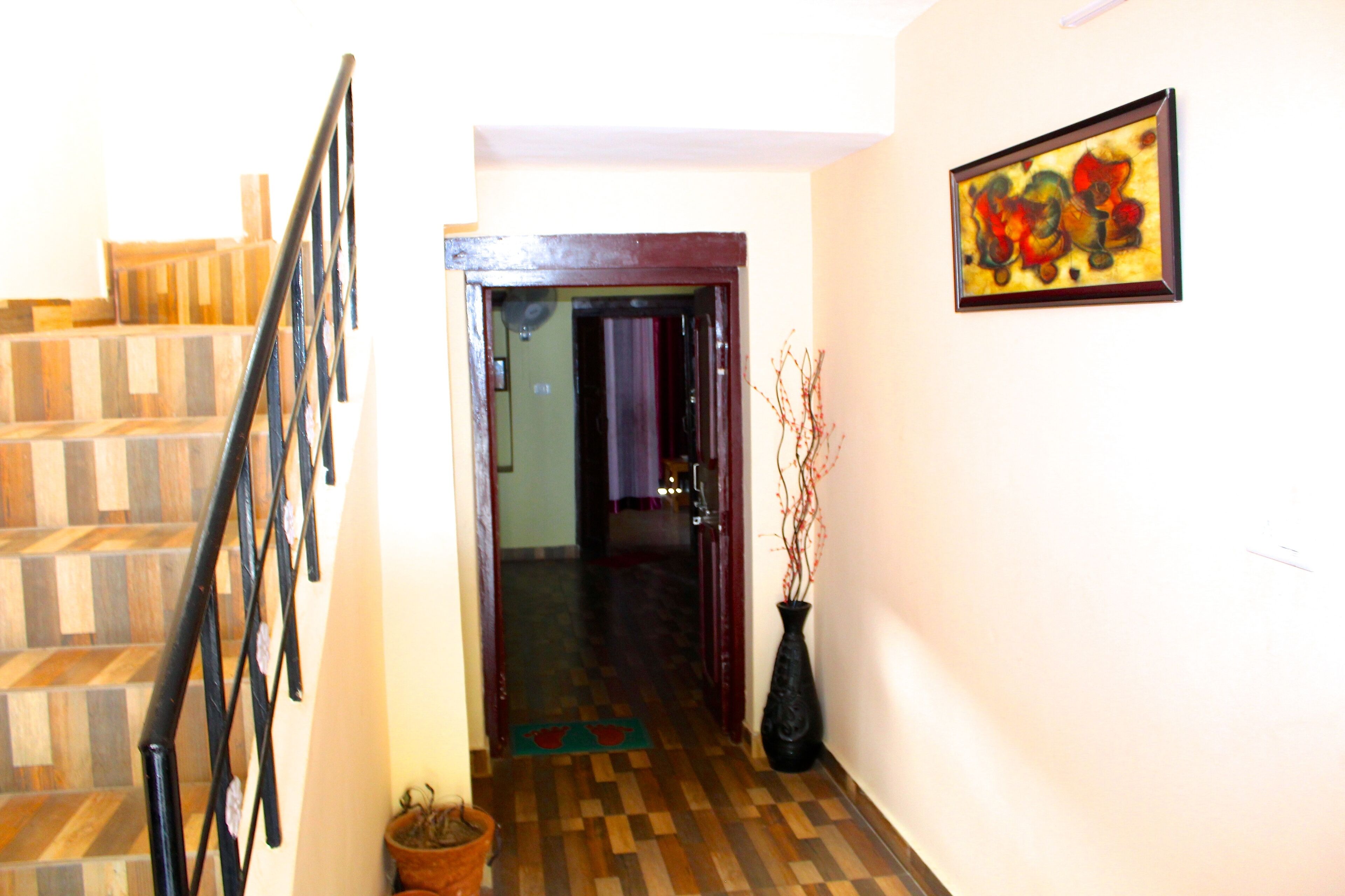 A staircase with a wooden finish, a black metal railing, and a door leading to another room.