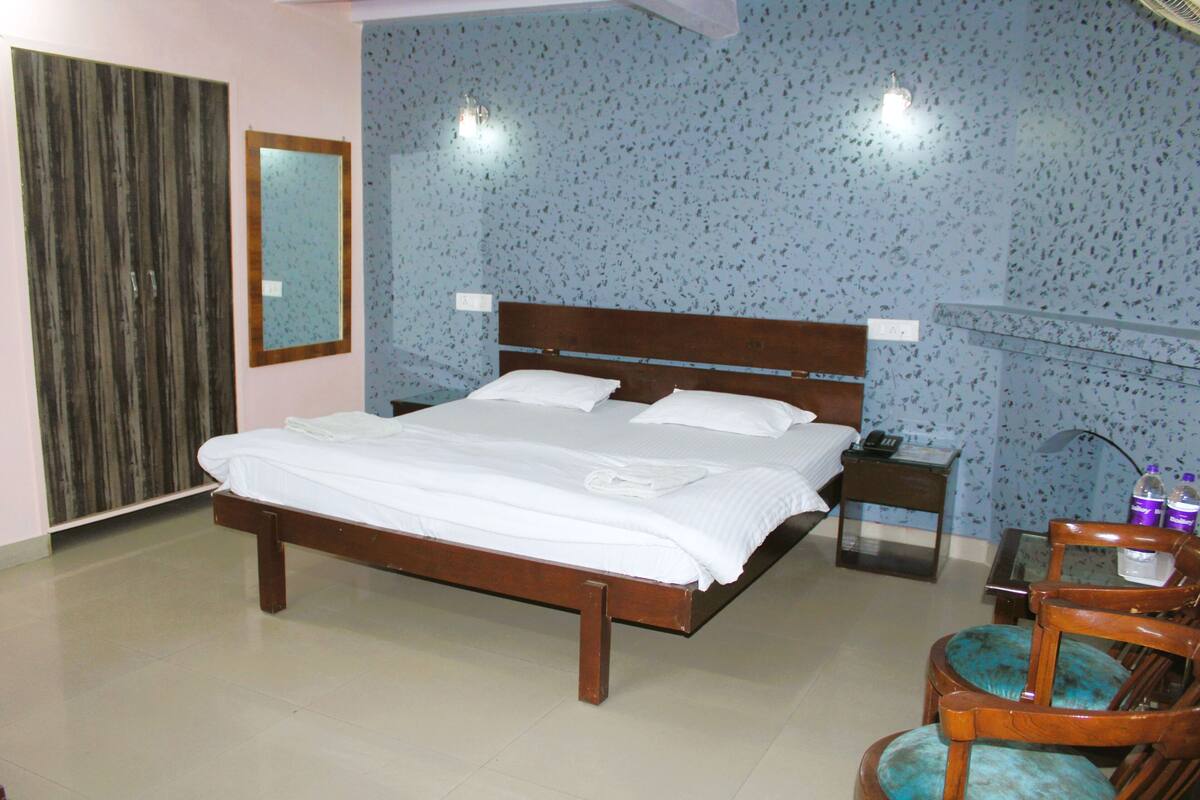 Un dormitorio con cama de madera, mesita de noche, silla y espejo en la pared.