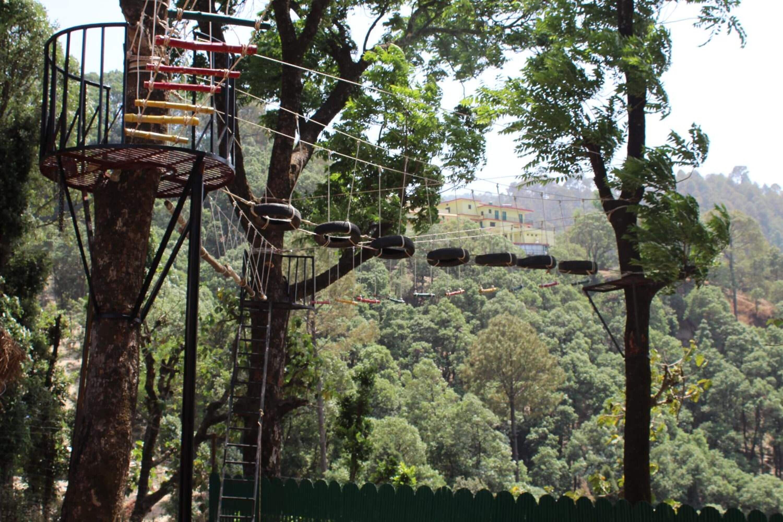 A treehouse with a rope bridge and a metal platform.