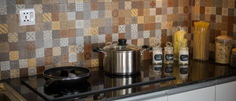A kitchen with a checkered backsplash, a stainless steel pot on the counter, and spice jars labeled "Sald," "Pepper," and "Sugar."