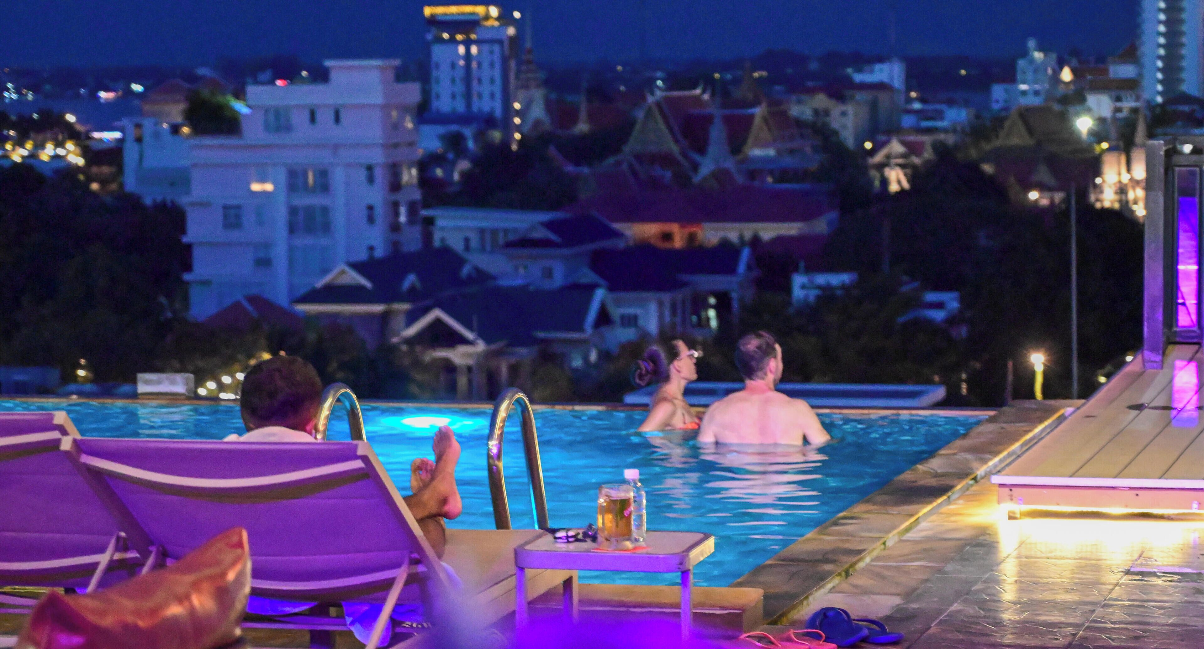 Zona de piscina con sillas de descanso y una mesa con una bebida.
