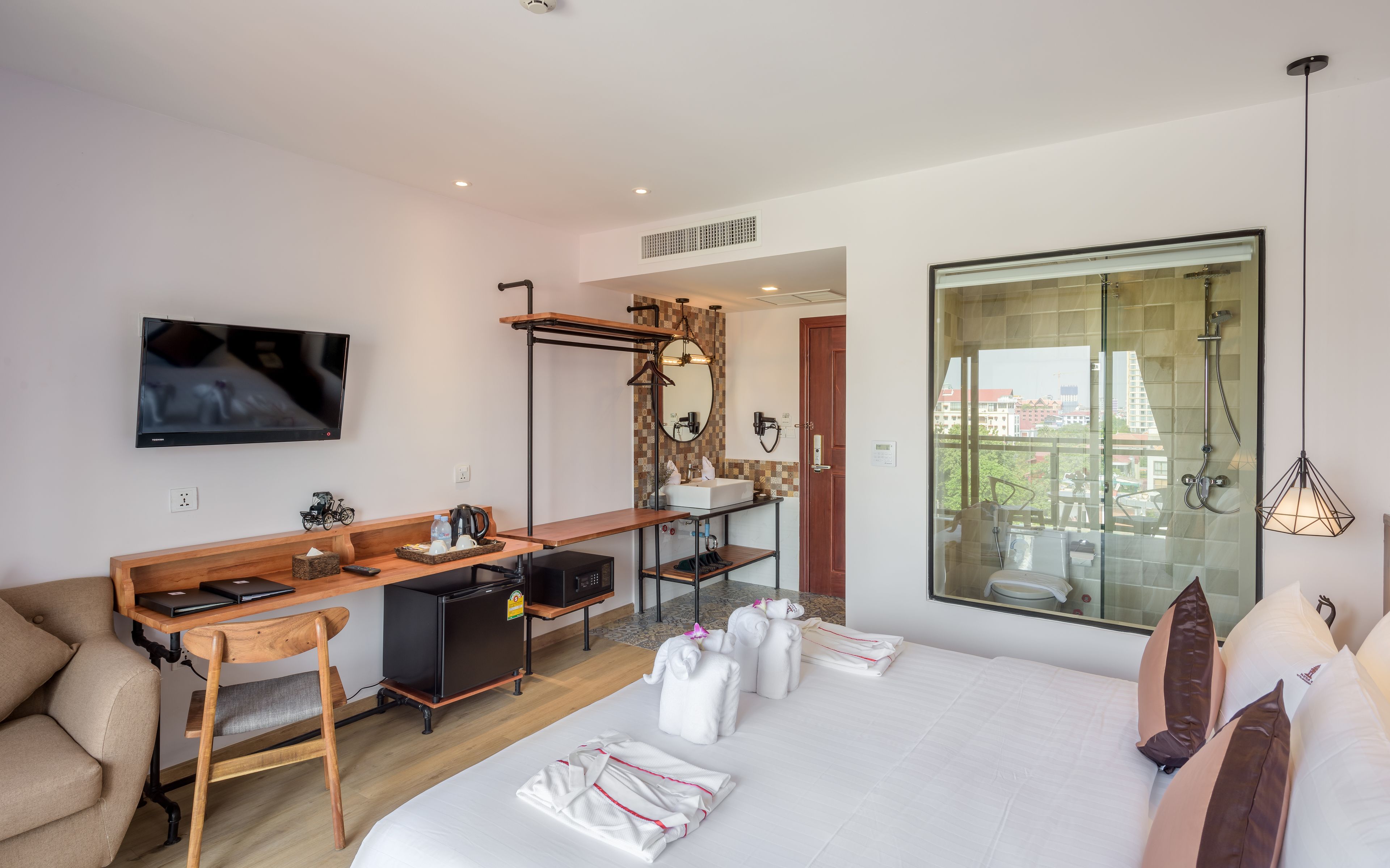 Une chambre d’hôtel avec un lit, un bureau, une télévision, une douche et une vue sur les immeubles.